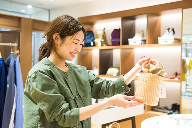 Spick滝沢さん 店内 かごバッグ選んでいるところ カーキジャケット着用